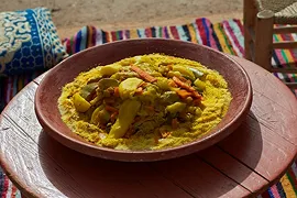 カラフルな敷物の上の木のテーブルにカレー風の食べ物